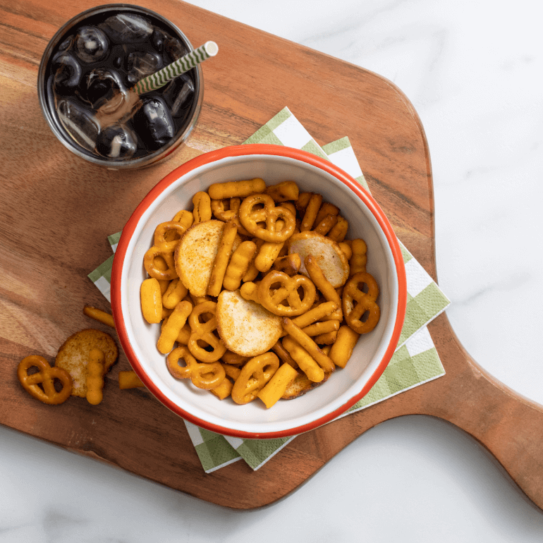 A bowl of Gardetto's Pizzeria blend on a cutting board with pepperoni and olives