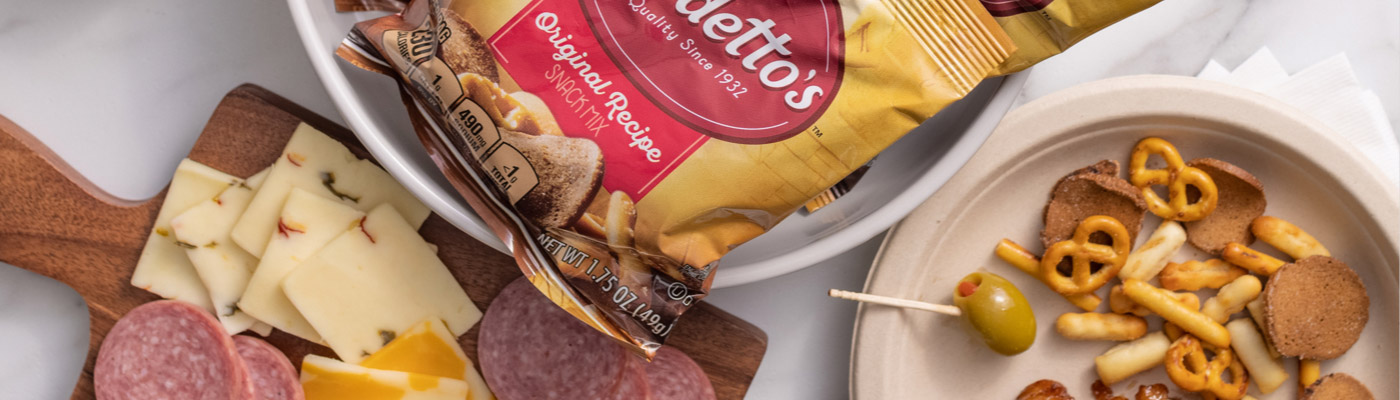 A plate of Gardetto's Original Recipe snack mix, a cheese and meat charcuterie board, alongside a bag of Gardetto's Original Recipe snack mix, front of pack